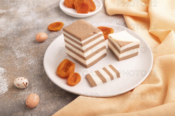 Cocoa and milk jelly with dried apricots on brown concrete background and orange textile, side