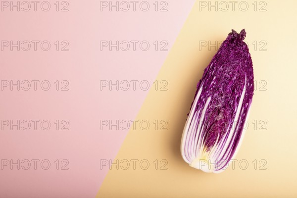 Purple Chinese cabbage on pink and orange pastel paper background, top view, flat lay, copy space,