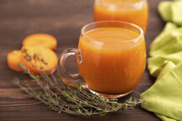 Two glasses with carrot juice, on wooden background and green textile. Diet, healthy eating concept