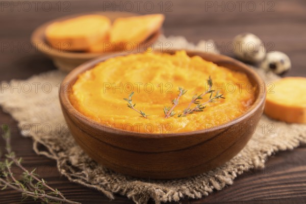 Sweet potato porridge in wooden bowl on wooden background and linen textile. Diet, healthy eating