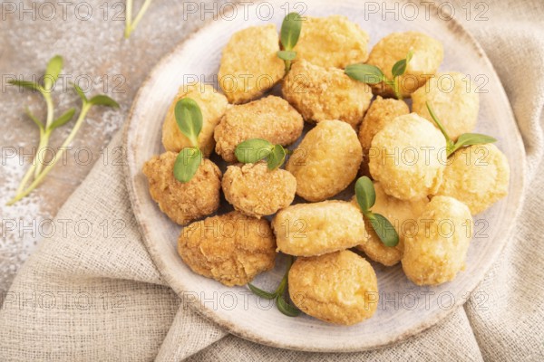 Fried crispy Chicken Nuggets with ketchup, microgreen on brown concrete background and linen