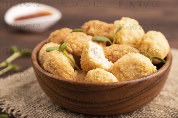 Fried crispy Chicken Nuggets with ketchup, microgreen on brown wooden background and linen textile.