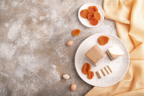 Cocoa and milk jelly with dried apricots on brown concrete background and orange textile, top view,