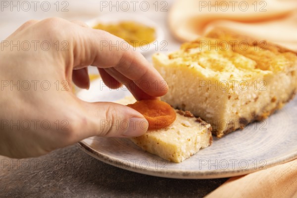 ?ottage cheese ?asserole, Curd cake, with dried apricots and raisins with hand on brown concrete