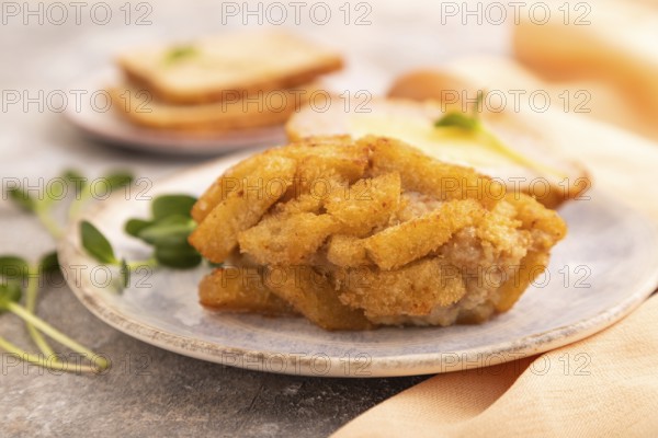Chicken Schnitzel on blue plate with microgreen on brown concrete background and orange linen