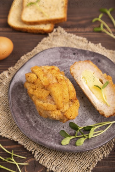 Chicken Schnitzel on gray plate with microgreen on brown wooden background and linen textile. side
