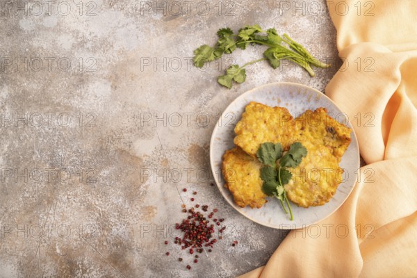 Fried crispy Chicken pancakes on brown concrete background and orange linen textile. top view, flat