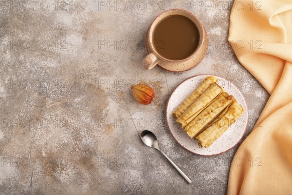 Waffles with caramel on brown concrete background and orange linen textile, cup of coffee, top