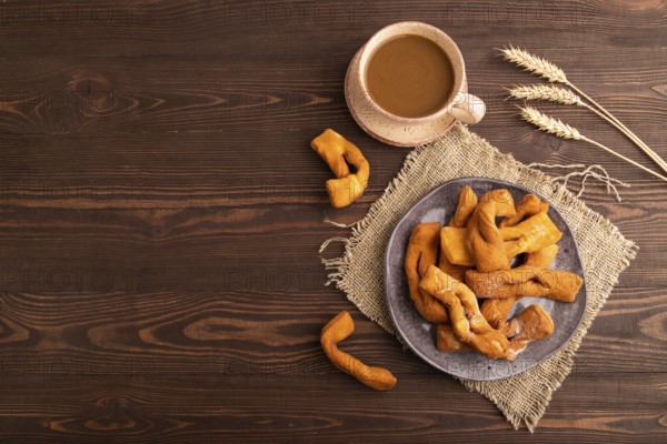 Crunchy biscuit Brushwood cookies sprinkled with powdered sugar on brown wooden background and