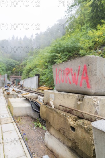 Baustelle mit Betonblöcken, auf einem steht rotes Graffiti 'Kurwa', Bau der Hermann Hessenahn,