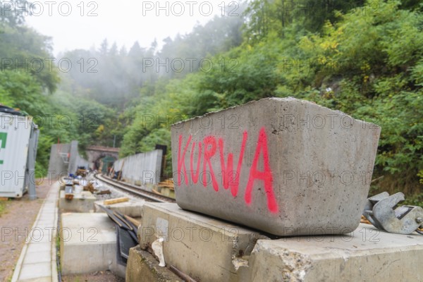 Mit 'Kurwa' beschriebene Betonblöcke auf einer Baustelle im Nebel, Bau der Hermann Hessenahn, Calw,