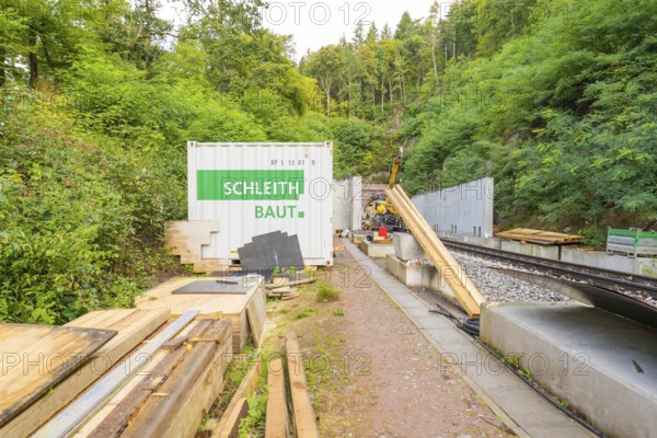 Schleith Baustellencontainer neben Schienen und Materialstapeln im Grünen, Bau der Hermann