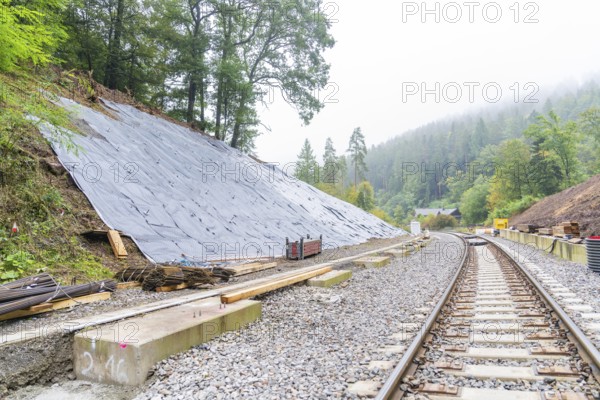 Bahnstrecke mit Gleisen entlang eines Hangs, gesichert durch Planen im Wald, Bau der Hermann