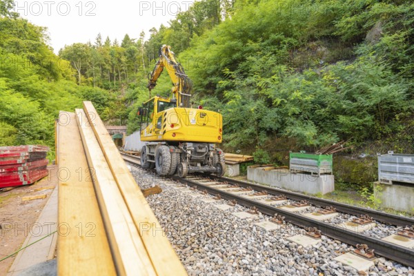 Baufahrzeug mit Kran auf Schienen in einer bewaldeten Baustelle, Bau der Hermann Hessenahn, Calw,