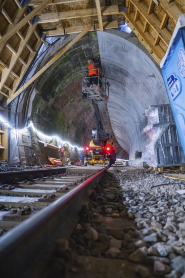 Tunnelbau mit Schienen, Maschinen, beleuchteter Atmosphäre und einem Bauarbeiter in Aktion, Bau der