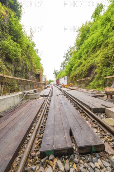 Eisenbahnschienen mit Holzplanken in einer eingefassten, grünen Bauumgebung, Bau der Hermann