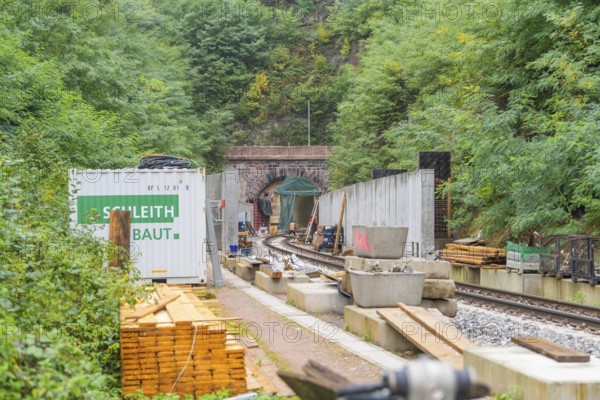Tunnelbaustelle mit Materialien und einem fernen Eingang umgeben von Wald, Bau der Hermann