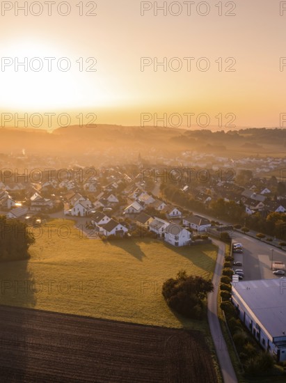 Dorfansicht bei Sonnenaufgang mit beleuchteten Dächern und umliegenden Feldern, Gechingen,
