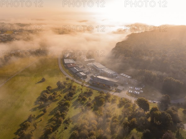Nebel und Morgensonne schaffen eine atmosphärische Landschaft über Industriegebäuden, Gechingen,