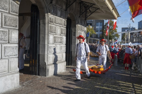 Männer mit Käse laufen durch ein historisches Marktgelände mit Publikum, ehemalige Stadtwaage,
