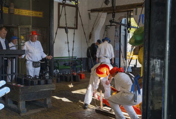 Männer in weiß mit roten Hüten bei der Arbeit auf einem Käsemarkt, ehemalige Stadtwaage, Käse
