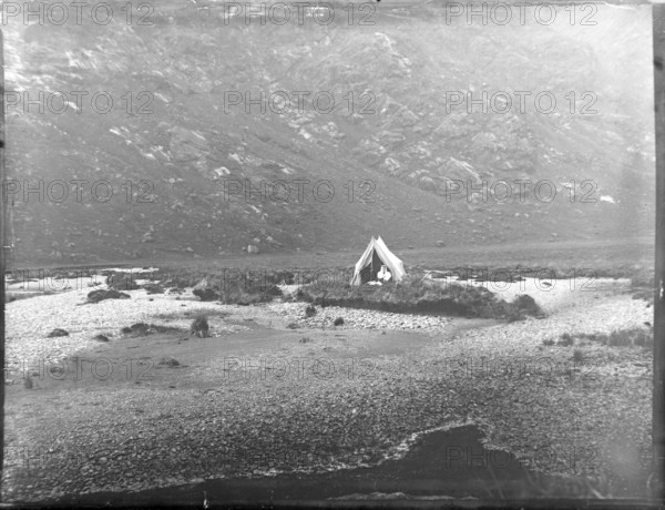 Tent camp on island in river of mountain valley, thought to be Cuillin mountains, Skye, Scotland,