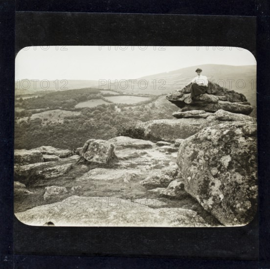 Magic lantern slide of woman sitting on mountain peak in countryside England, UK circa 1900