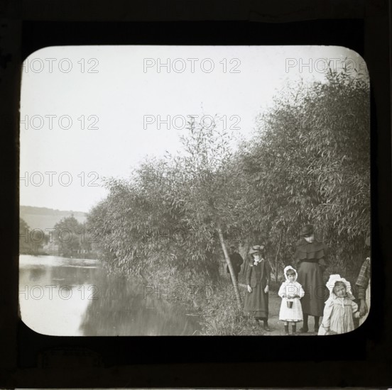 Magic lanterns slide of Edwardian children walking on a footpath next to a river, England, UK c