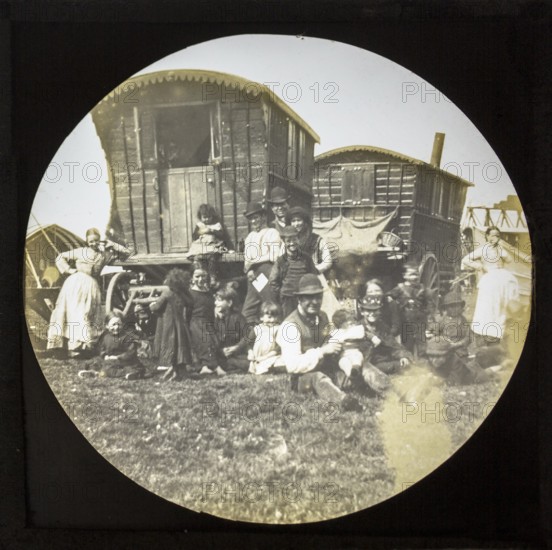 Magic lantern slide portrait of fairground travelling gypsy extended family and caravans, UK circa