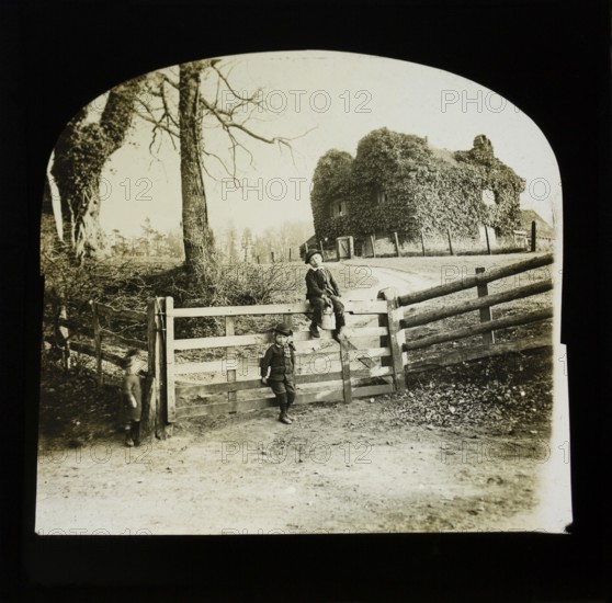 Magic lantern slide of children by gate entrance with mysterious looking ivy covered house standing