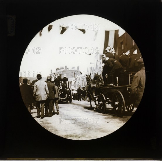 Horse drawn fire engines procession at a patriotic event with bunting flags across the street,