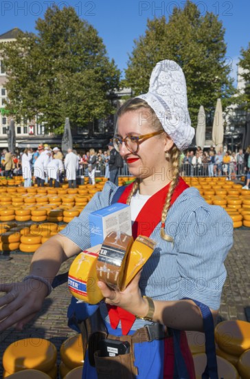 Woman in traditional traditional costume selling pieces of cheese at a market in sunny weather,