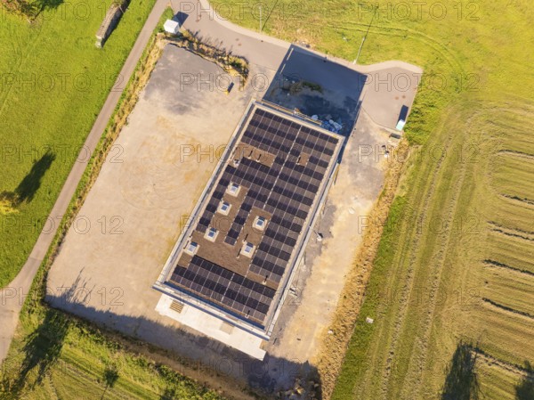 Top view of solar roof of a building with surrounding fields and car park, new building with green