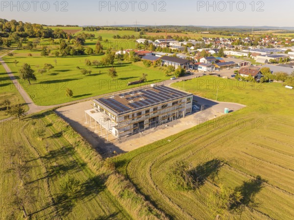 New building with solar panels, embedded in green fields, near a village, new building with green