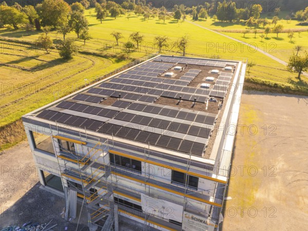 Building with solar panels and scaffolding in a green landscape, new building with green roof and