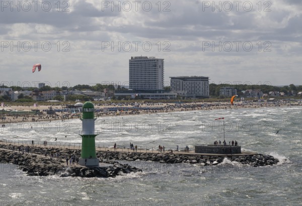 Green and white lighthouse, pier light Westmole in front of lively beach and hotels in the