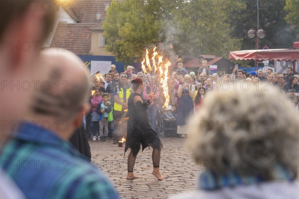 Dancer with burning torch, surrounded by an attentive audience at a street festival, Fire Night,