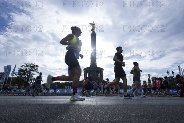 Runners run around the Victory Column against the backlight of the sun on the Great Star at the