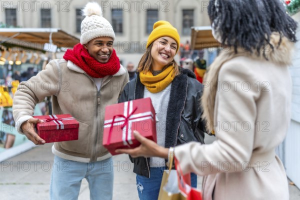 Happy friends exchanging christmas gifts at a bustling market, enjoying the festive atmosphere and