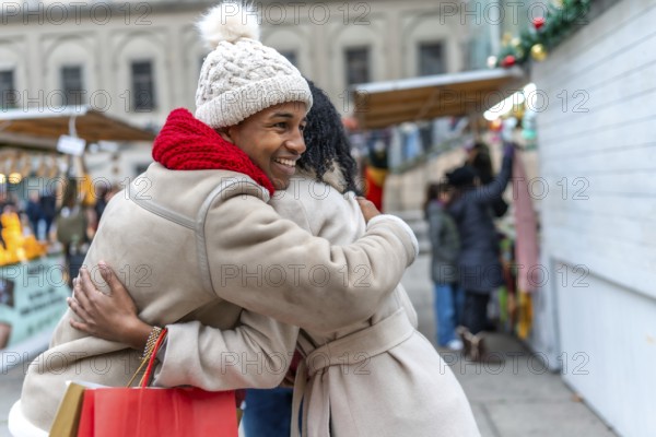 Two happy friends are hugging at a christmas market in a winter city, enjoying the festive