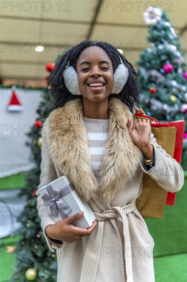 Happy customer holding a christmas present and shopping bags, enjoying winter sales in a decorated