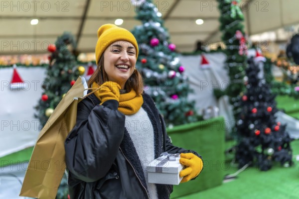 Smiling woman carrying shopping bags and gift box enjoying christmas shopping at a decorated