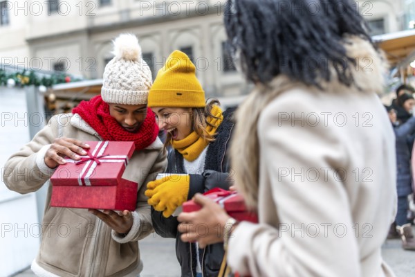 Happy friends joyfully exchanging christmas gifts at a bustling market, celebrating the festive