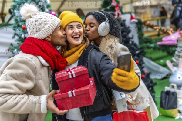 Three happy friends kissing a girl holding christmas gifts and taking a selfie at a christmas