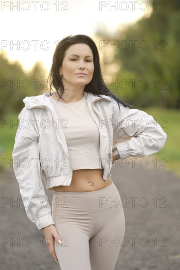 Confidently posing in a scenic park, a fitness enthusiast showcases her athletic style in a light