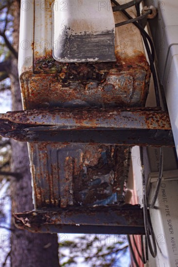 An old and rusty air conditioner hanging on the hotel building, in the sunny outdoor, seaside