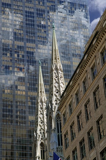 Towers of St Patrick's Cathedral in front of the facade of a skyscraper, Manhattan, New York City,