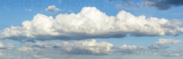 Panoramic photo of long white stratocumulus cloud, in the background more cumulus clouds,