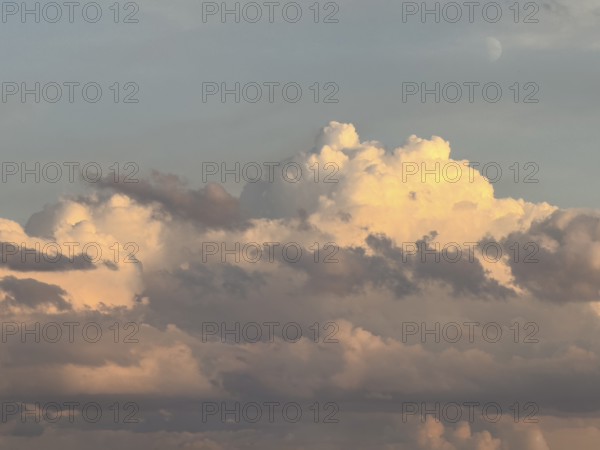 Mystical impression of cumulus cluster clouds at dusk illuminated by warm light, in the background