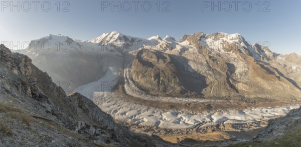 At dawn, the sun bathes the peaks of the Alps in a golden light and reveals stunning glaciers and